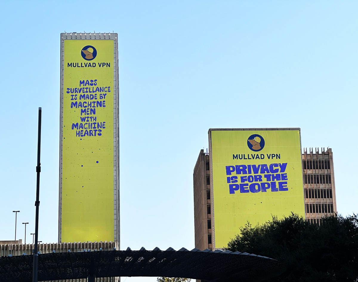 Yellow Mullvad VPN billboards: 'Mass surveillance is made by machine men with machine hearts' and 'Privacy is for the people' on city buildings.